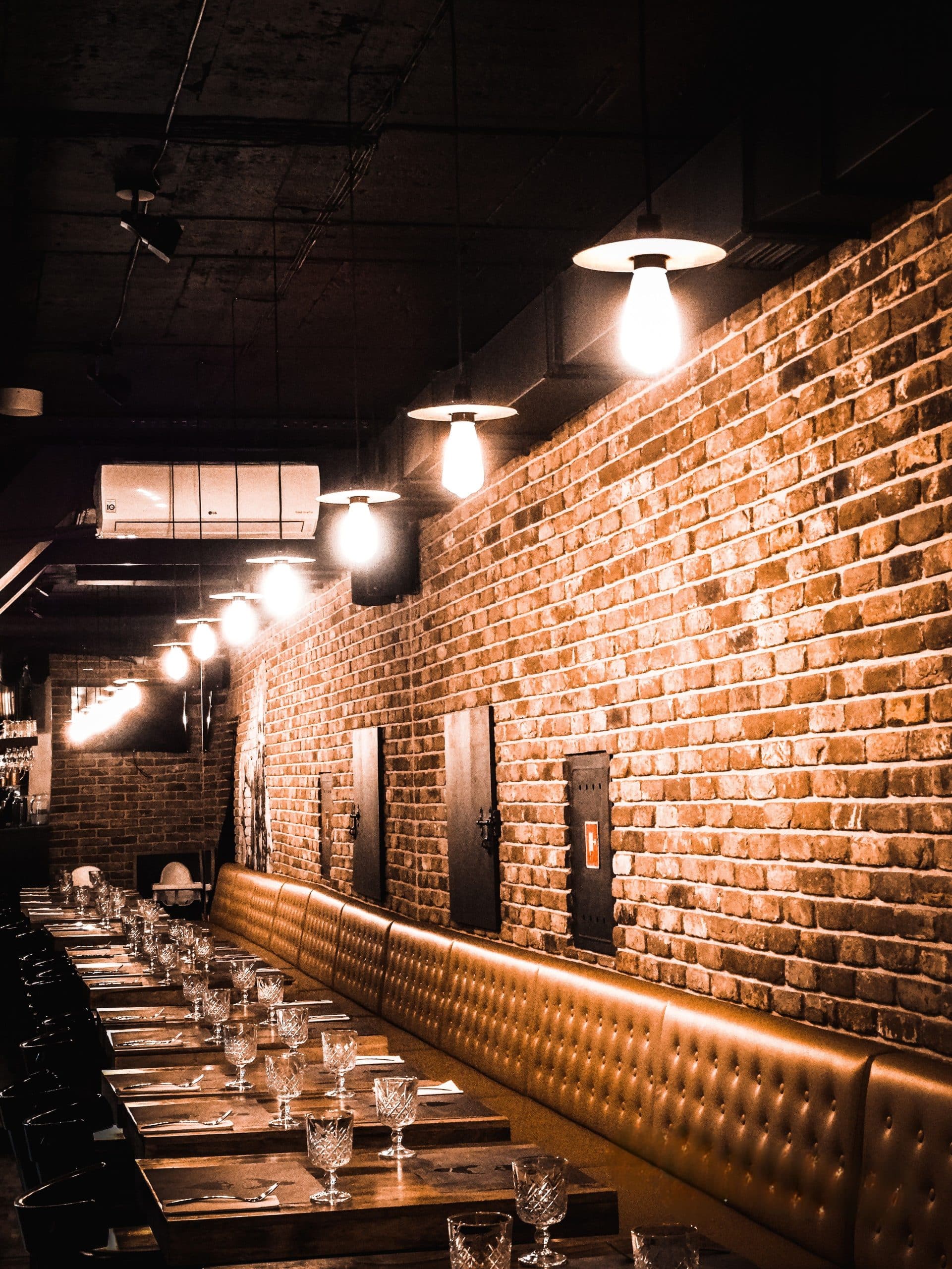 cozy, elegant Indian restaurant interior designed to appeal to Polish guests, featuring warm ambient lighting, exposed brick walls, comfortable leather seating, and beautifully set tables - inviting, modern, and perfect for a relaxed dining experience