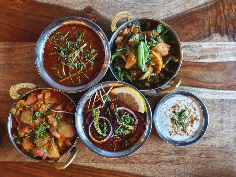 vibrant Indian dishes served in traditional bowls for lunch, featuring rich curries, aromatic spices, and fresh garnishes - an inviting, colorful spread crafted to delight Polish diners exploring authentic Indian cuisine